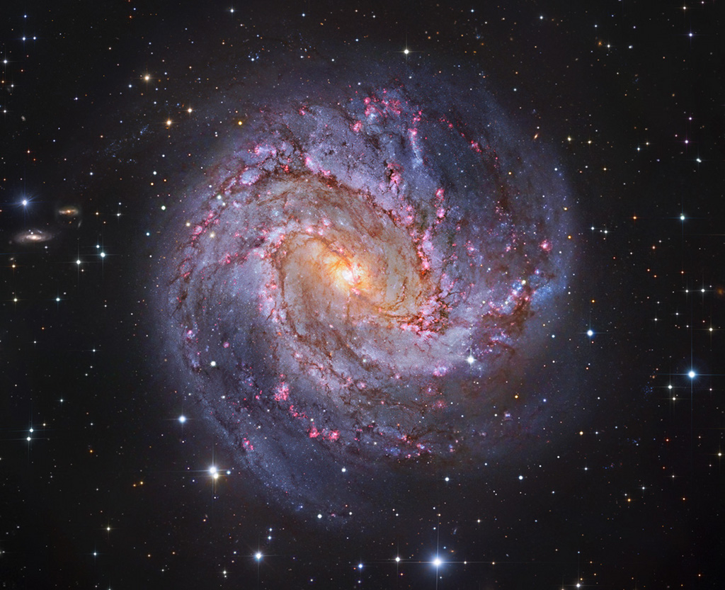 Die Spiralgalaxie M83 im Sternbild Wasserschlange hat markante Spiralarme. Sie sind von dunklen Staubbahnen, blauen Sternhaufen und rot leuchtenden Sternbildungsgebieten gesäumt.