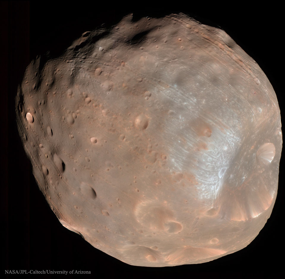 Der Marsmond Phobos ist hier bildfüllend dargestellt. Rechts ist ein riesiger Krater. Der ganze Mond ist von Kratern übersät. Sehr auffällig sind die Rillen, die parallel über die Oberfläche verlaufen. Sie sind vielleicht ein Hinweis auf die starken Gezeitenkräfte, die den Mond eines Tages vermutlich zerlegen.