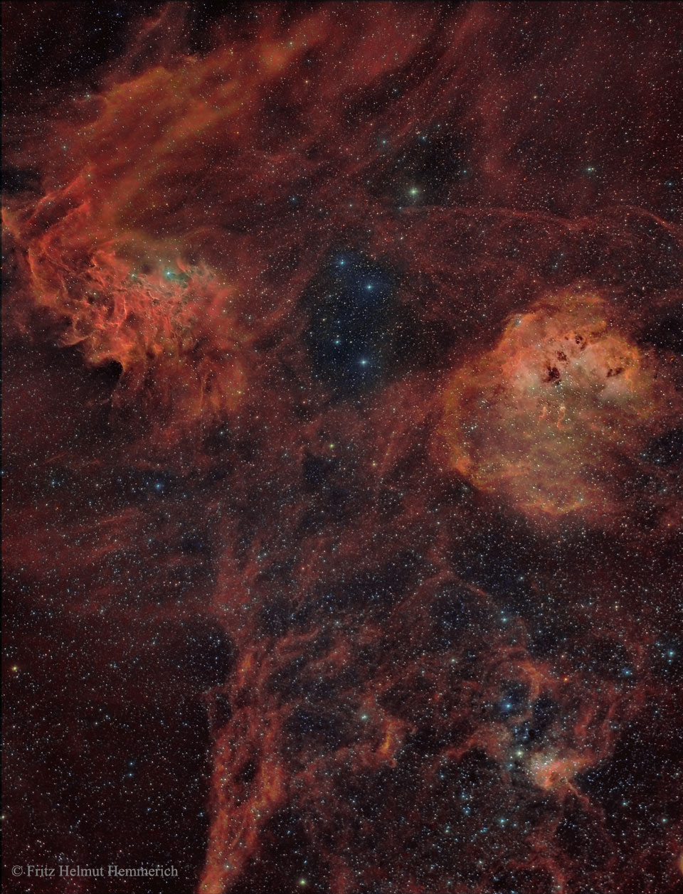 Das Bild ist dicht von kleinen Sternen übersät. Hinten sind dichte, teils stark strukturierte, rot leuchtende Nebelwolken verteilt. Rechts ist der Kaulquappennebel, unten sind die Spinne und die Fliege, links oben leuchtet die Emissionsregion IC 405, der Flammensternnebel.