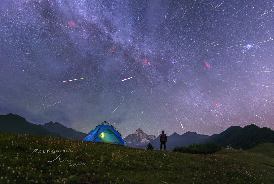 Hinter einem Zelt ist eine nächtliche Berglandschaft mit Gipfeln. Am Himmel darüber ziehen zahllose Meteore der Perseïden ihre Spuren an einem sternklaren Himmel mit vielen interessanten Himmelsobjekten. Sie strömen von einem Radianten im Sternbild Perseus aus.