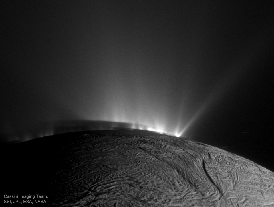Über der rissigen Oberfläche von Enceladus steigen am oberen Rand helle Eisschwaden strahlenförmig auf.