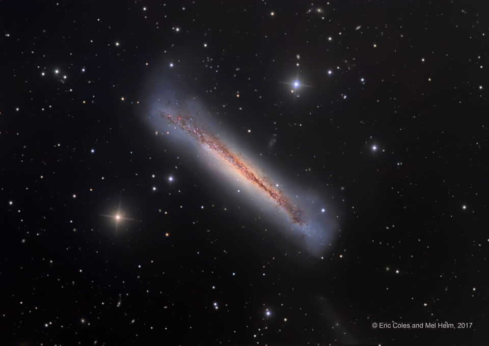 Die Galaxie NGC 3628 im Sternbild Löwe liegt schräg im Bild. Wir sehen sie von der Kante. Die Galaxie wirkt aufgebauscht, durch die Mitte verläuft eine Staubbahn.