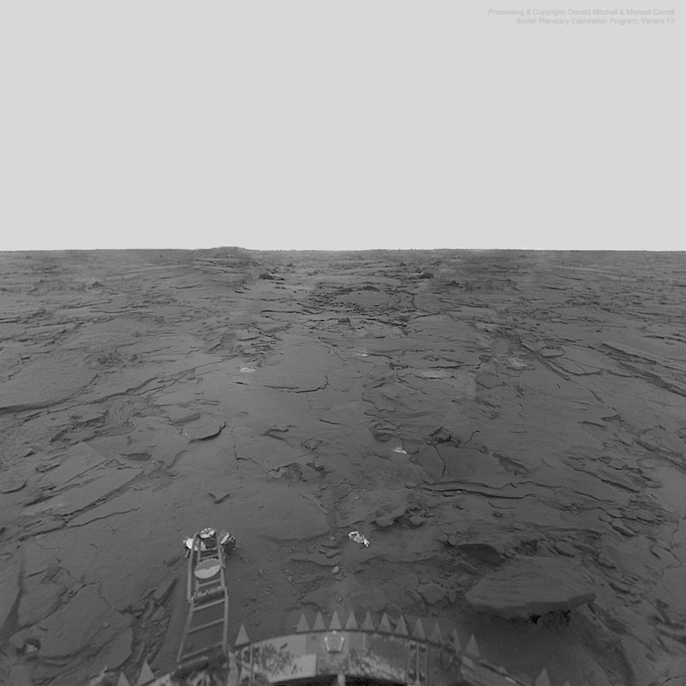 Aussicht der Landesonde Venera 13 auf der Oberfläche der Venus. In einer trostlosen Landschaft sind flache Felsen verteilt, unten sieht man den Rand der Sonde.