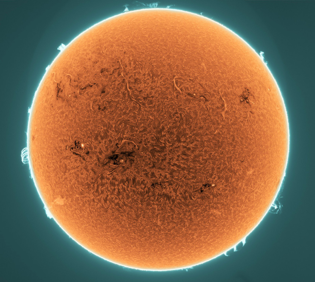 Die orangefarbene Sonne hat einen sehr hellen Rand und ist von einem türisblauen Hintergrund umgeben.
