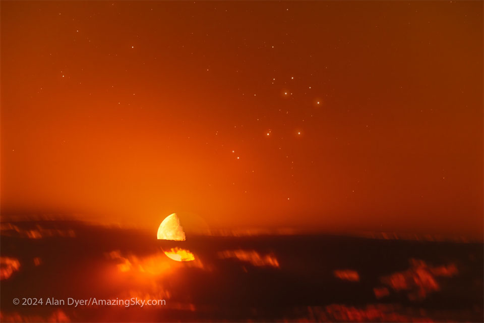 Der Halbmond ist links unter der Mitte teilweise von einer Wolkensträhne bedeckt. Am tiefroten Himmel steht rechts über der Mitte der Sternhaufen der Plejaden.