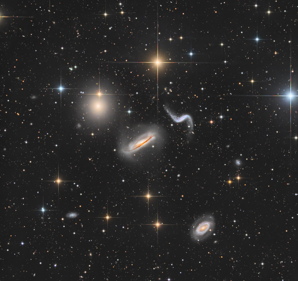 Die Galaxien von Hickson 44 im Sternbild Löwe wirken verzerrt. Es sind Spiralgalaxien mit ausgeprägten Staubbahnen oder ausgezogenen Spiralarmen. Sie sind zwischen bunten Sternen verteilt.