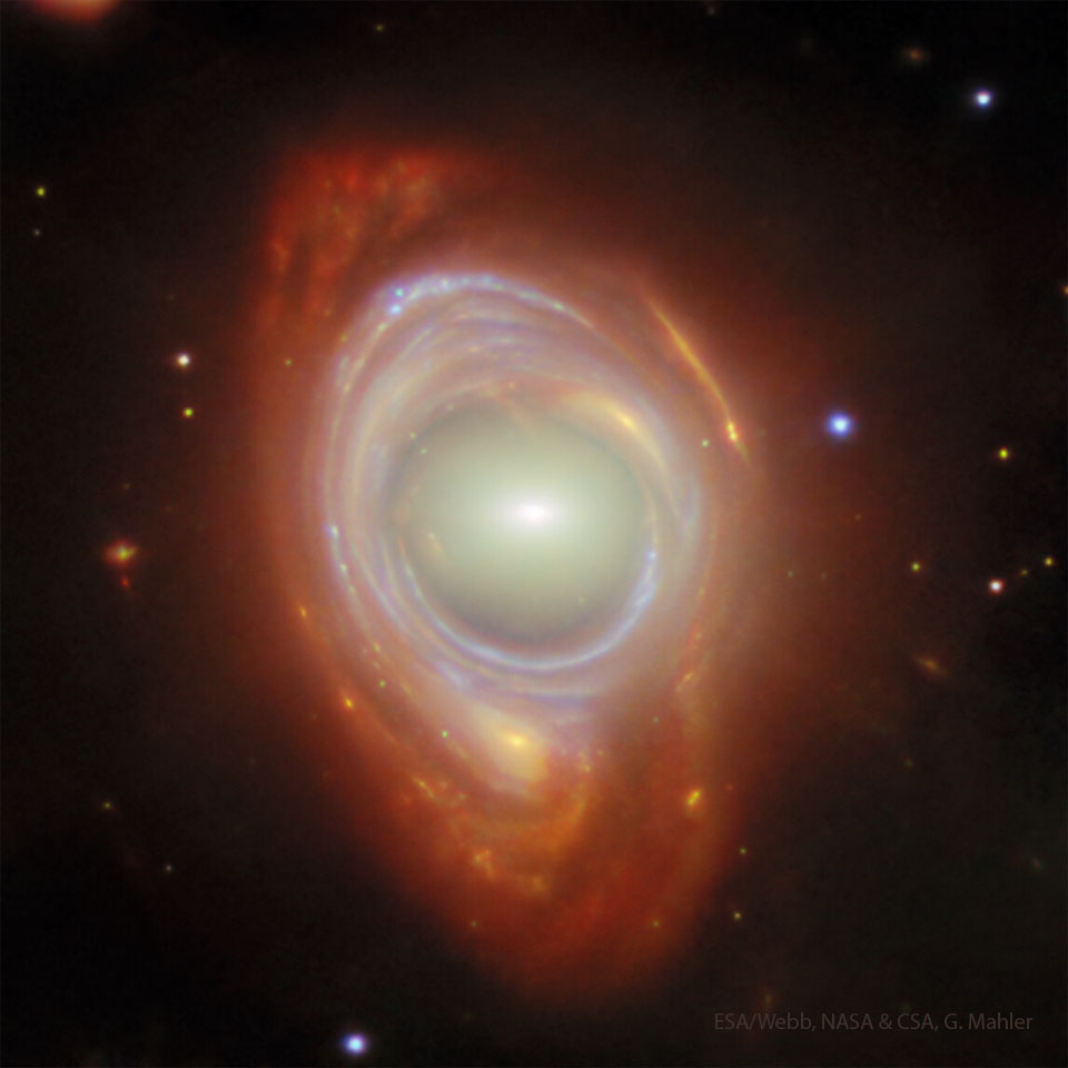 Eine elliptische hell leuchtende Galaxie ist von einem verzerrt wirkenden Spiralgalaxie in blauen und roten Farbtönen umgeben.