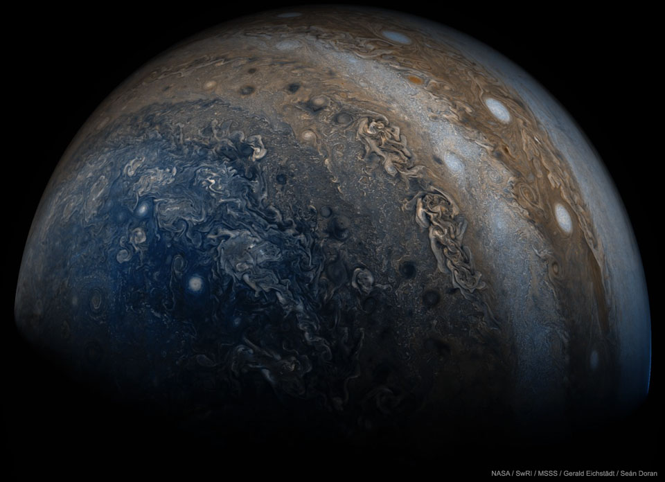 Die Nahaufnahme zeigt den Planeten Jupiter mit vielen Wolken, darunter blaue Wolken links unten und weiße ovale Wolken rechts oben.