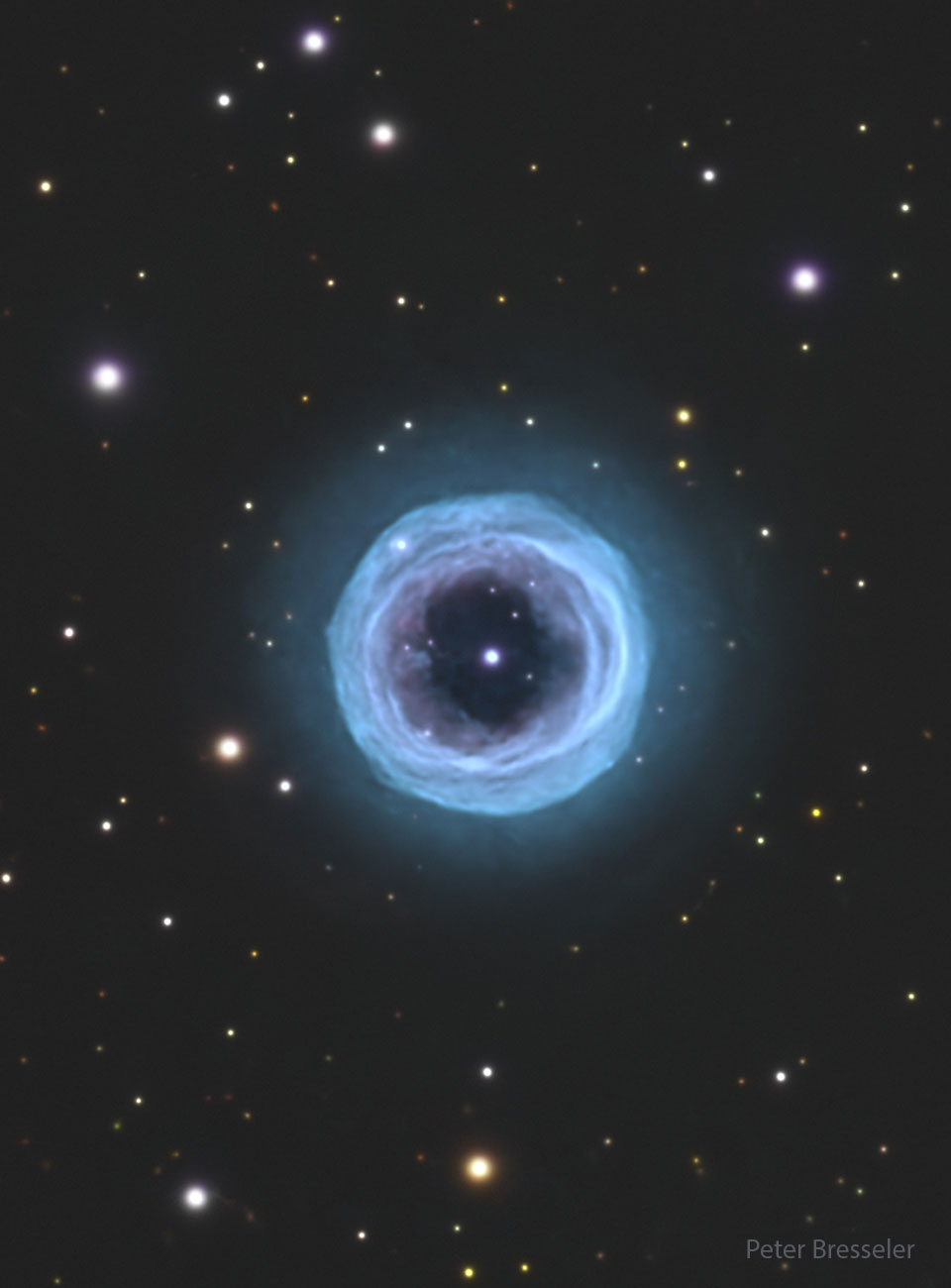 Auf einem dunklen Hintergrund mit Sternen steht ein blauer, nebliger Ring. In seiner Mitte leuchtet ein heller Stern.